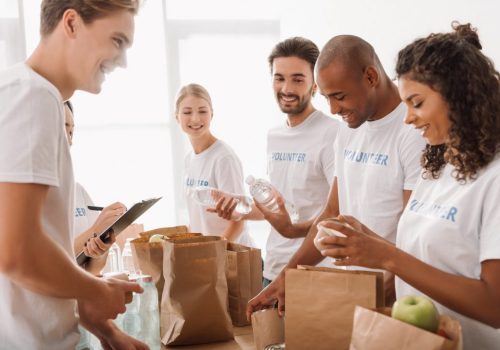 young-multiethnic-group-of-volunteers-putting-food-and-drinks-in-paper-bags-for-charity.jpg